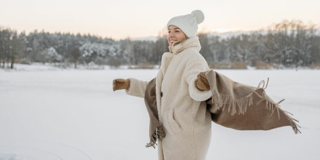 Femme dans la neige, heureuse après sa routine, portant une tenue blanche d'hiver